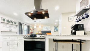 A modern kitchen with a built-in oven, stainless steel range hood, and a marble countertop. - Walk to the AT&T Stadium, Texas Rangers Globe Life Park, Texas Live & many more. (Arlington)