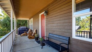 A covered porch with a bench, chairs, and a grill. - Devon Court - Adorable Remodeled, Quiet, Near Town, Fenced Yard, Pet Friendly (Hood River)