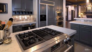 A modern kitchen with dark cabinetry, a gas range, a built-in oven, and a stone accent wall. - Fairway to Heaven-Luxury at Club of CB, Hot tub! (Crested Butte)