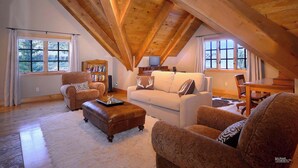 A cozy loft-style living room with a high wooden ceiling, a white sofa, brown armchairs, and a fireplace. - Fairway to Heaven-Luxury at Club of CB, Hot tub! (Crested Butte)