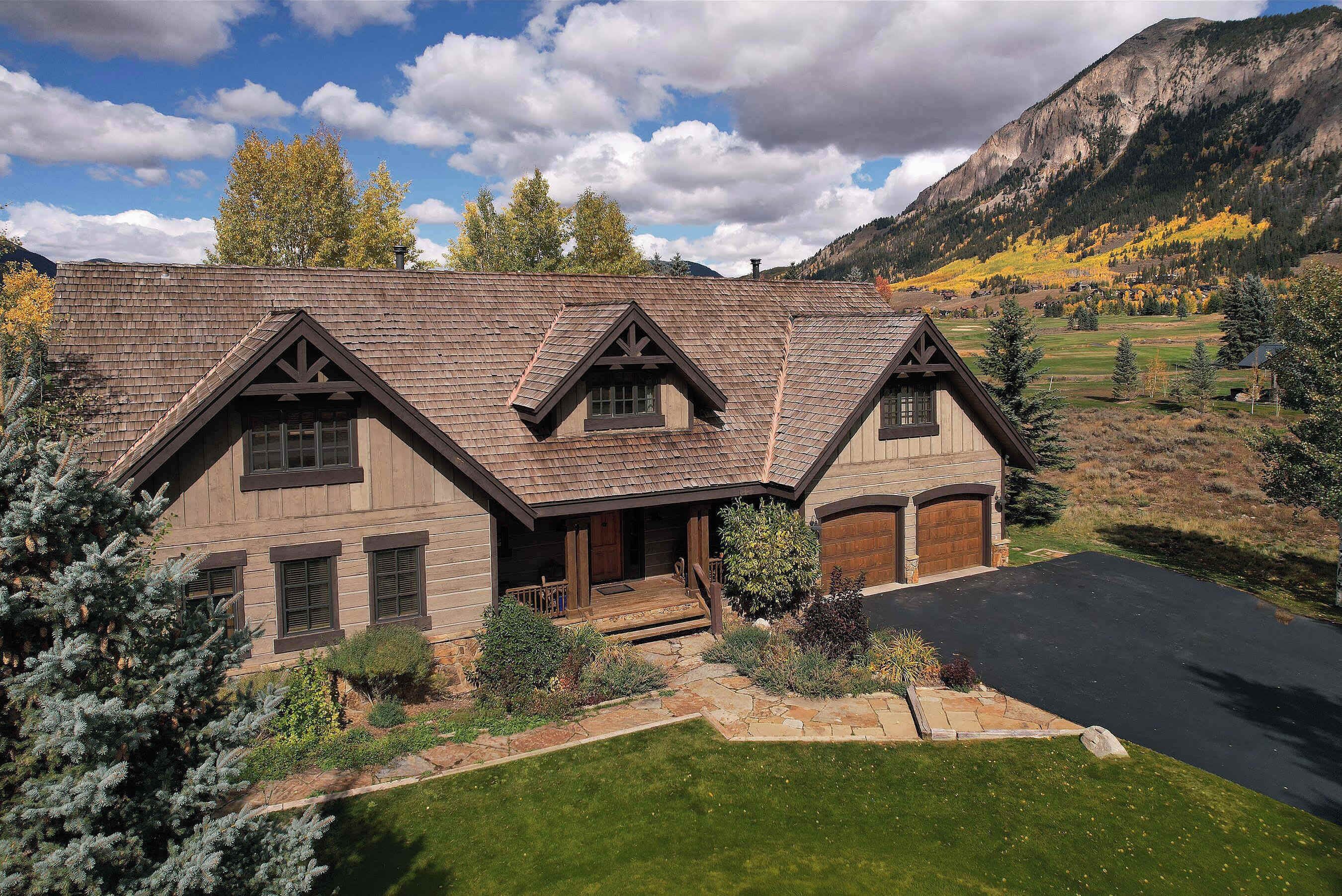 A large, two-story house with a steeply pitched roof, a front porch, and a stone foundation.