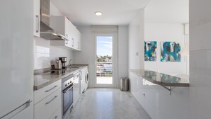 A modern kitchen with stainless steel appliances, a built-in oven, and a washing machine. - Nice Apartment with a Sunny Terrace, Pool & Sea View (Benalmádena)