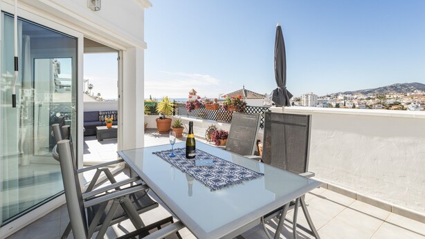 A balcony with a table, chairs, a bottle of wine, and a view of the cityscape. - Homely apartment, 2 big terraces, stunning views and pool (Nerja)
