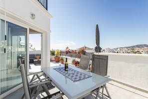 A balcony with a table, chairs, a bottle of wine, and a view of the cityscape. - Homely apartment, 2 big terraces, stunning views and pool (Nerja)