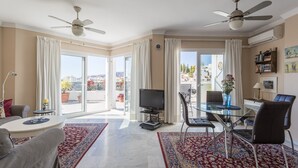 A spacious living room with a TV, seating, and a balcony with a view. - Homely apartment, 2 big terraces, stunning views and pool (Nerja)