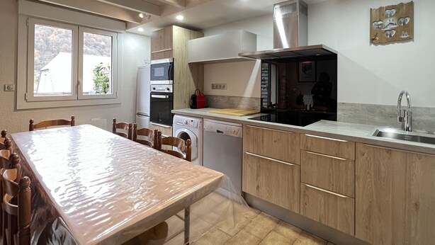 Una cocina con armarios de madera, horno empotrado, microondas, lavavajillas y un lavabo.