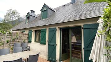 A house with a deck, green shutters, and a sliding glass door.