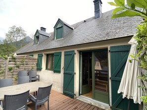 A house with a patio, a dining table with chairs, and a sliding glass door.