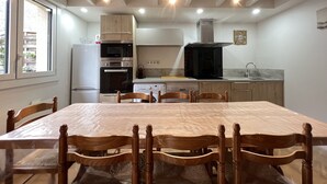 Una cocina moderna con electrodomésticos integrados, una mesa de comedor con sillas y vistas al exterior.
