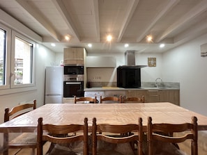 A modern kitchen with built-in appliances, a dining table with chairs, and a view of the outdoors.