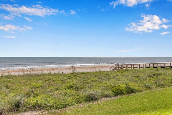 A beach with a wooden boardwalk leading to the shore.