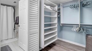 A walk-in closet with open shelving, a hanging rod, and a door with a towel hanging on it.