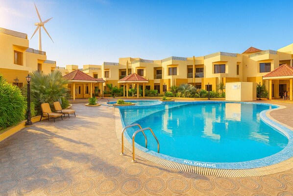 A hotel with a swimming pool, lounge chairs, and a wind turbine. - The Sky Imperial Bapu’s Resort (Dwarka)