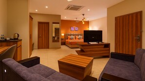 Ein modernes Hotelzimmer mit Fernseher, Sofa, Couchtisch und Schreibtisch mit Wasserkocher.