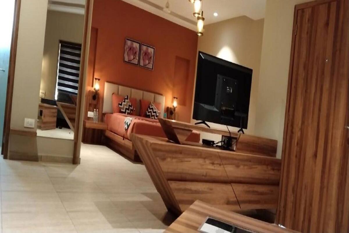 A bedroom with a bed, a TV, a wooden desk, and a staircase.