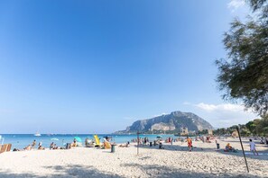 A beach with people, umbrellas, and a mountain in the background. - Charming holiday home in Mondello with terrace (Palermo)
