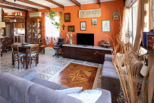 A cozy living room with a dining area, a TV, and a fireplace. - Charming holiday home in Mondello with terrace (Palermo)