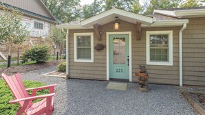 A house with a green door, number 223, a welcome bear statue, and a red chair outside.
