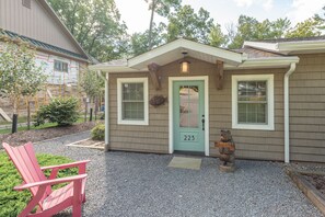 A house with a green door, number 223, a welcome bear statue, and a red chair outside.