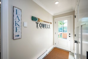 Um corredor com uma porta branca, uma pá de madeira e decoração nas paredes incluindo 'LAKE' e 'TOWELS'.