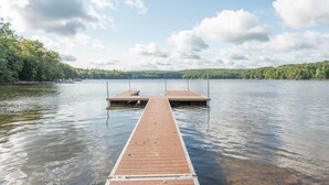 A wooden pier extending into a calm lake with a clear sky and distant hills.