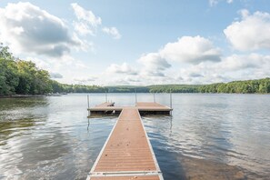 A wooden pier extending into a calm lake with a clear sky and distant hills.