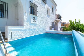 Une piscine à l’eau d’un bleu cristallin, un bâtiment blanc doté de balcons et une enseigne indiquant « Casa Lovisa ».