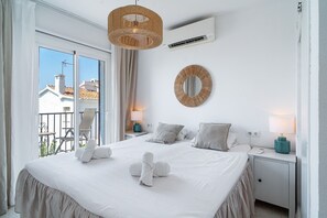 Une chambre d’hôtel avec un lit, deux tables de chevet, un miroir rond et une vue sur l’extérieur.