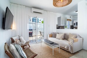 Una sala moderna con sofá, mesa de centro, televisor y un comedor con sillas.