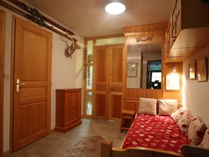 A room with a bed, wooden wardrobe, and a mirror.