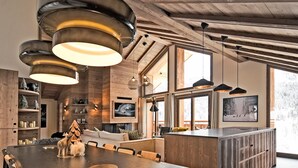 Una cocina moderna con una isla grande, vigas de madera e iluminación colgante.
