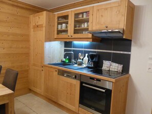 A kitchen with wooden cabinets, a black countertop, a Bosch oven, and a coffee maker. - Modern Apartment - 2BR - Sleeps 6 - Balcony - Mountain Views - Ski Shuttle - Village Center Nearby (Arêches-Beaufort)