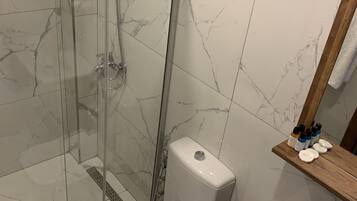 Een badkamer met een douchecabine van glas, toilet en wastafel.