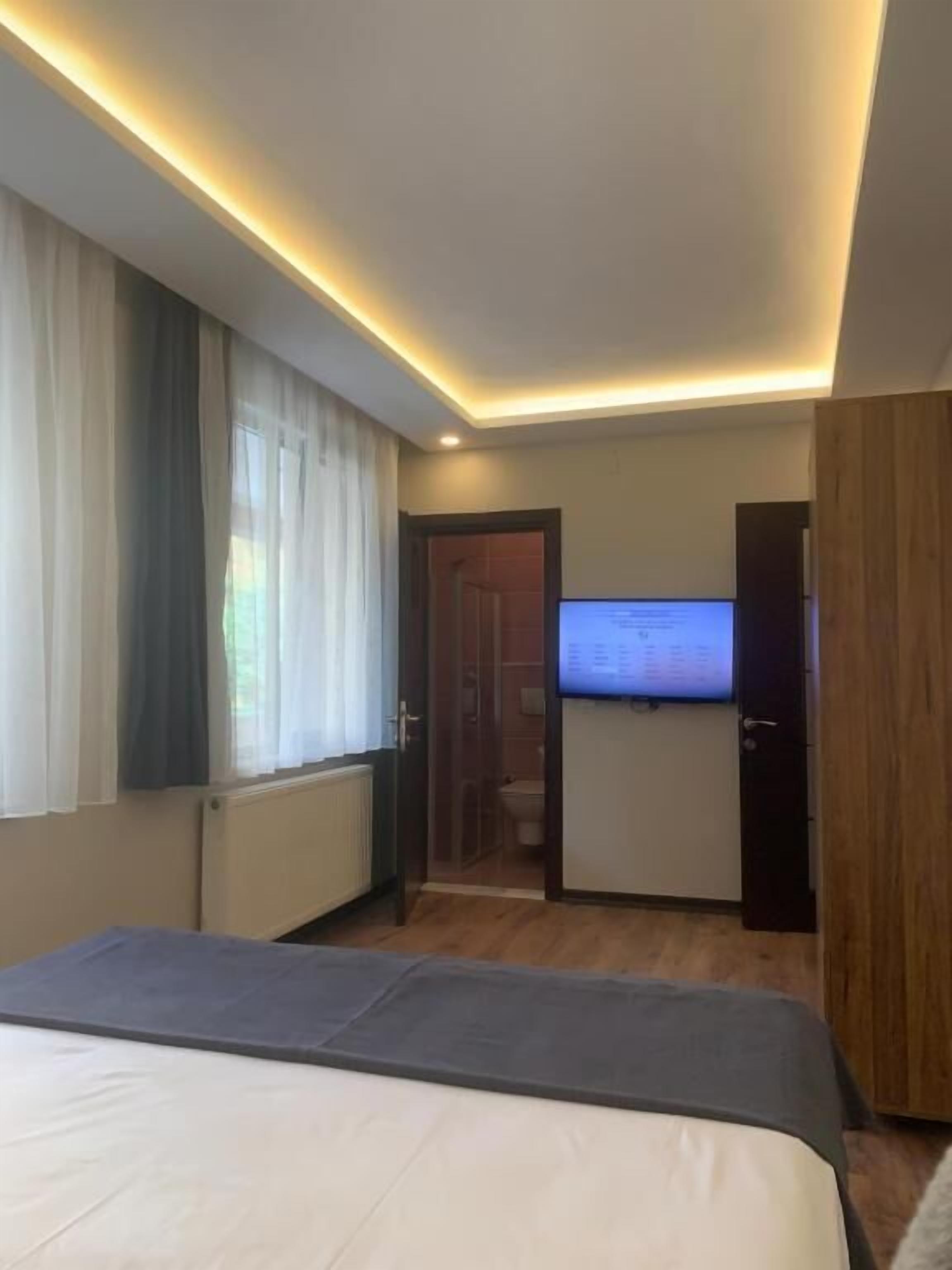 Un dormitorio moderno con una cama, un televisor y una puerta que da a un baño.
