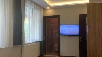 Un dormitorio moderno con una cama, un televisor y una puerta que da a un baño.
