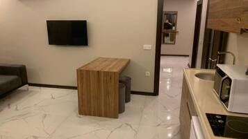 A modern living room with a flat-screen TV, a wooden coffee table, and a marble floor.