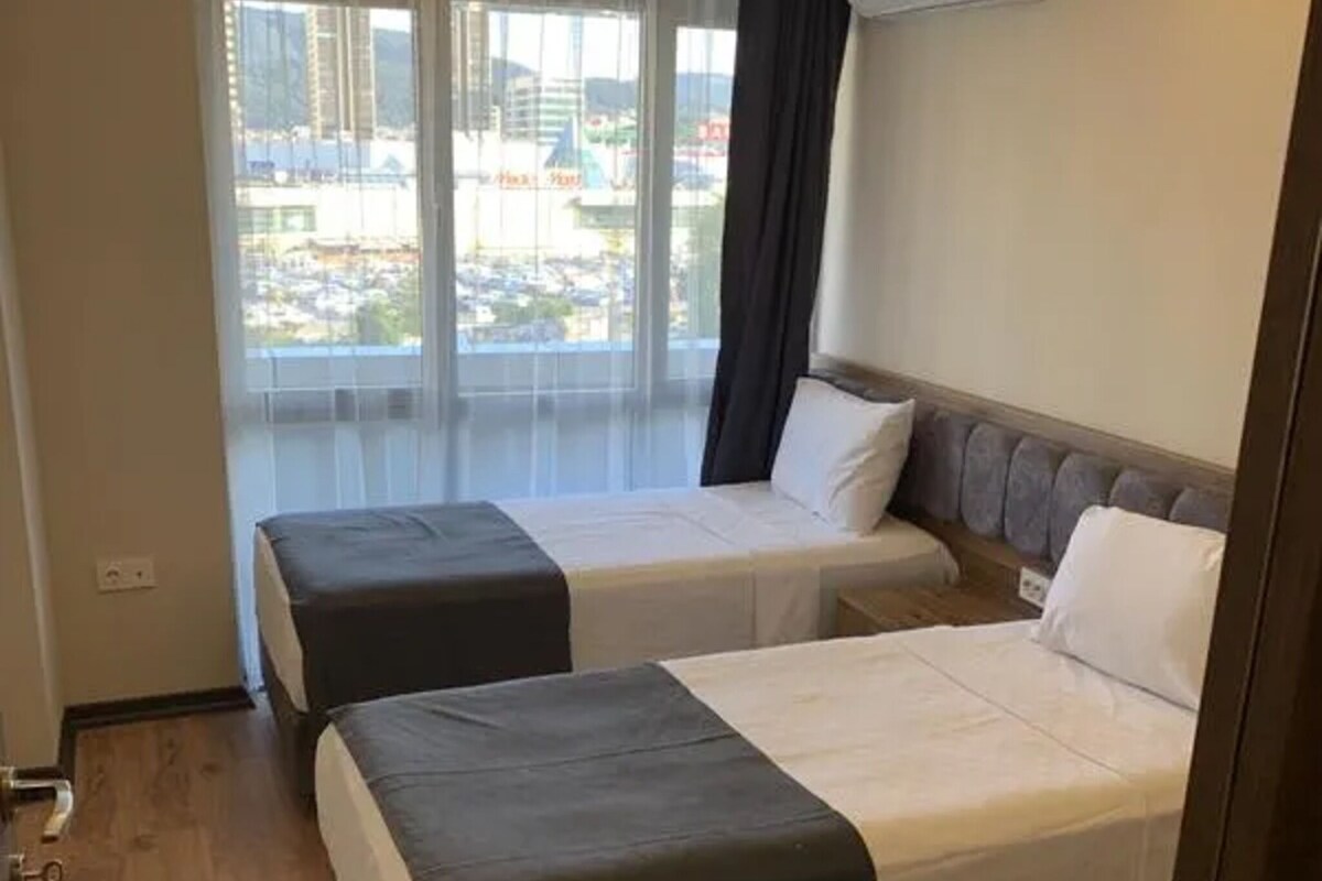 Habitación de hotel con dos camas, un ventanal con vistas y un equipo de aire acondicionado en la pared.