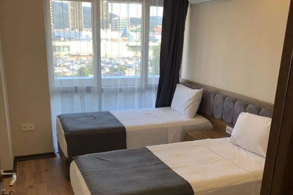 Habitación de hotel con dos camas, un ventanal con vistas y un equipo de aire acondicionado en la pared.