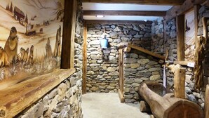 A rustic interior with stone walls, wooden beams, and a mural depicting wildlife.
