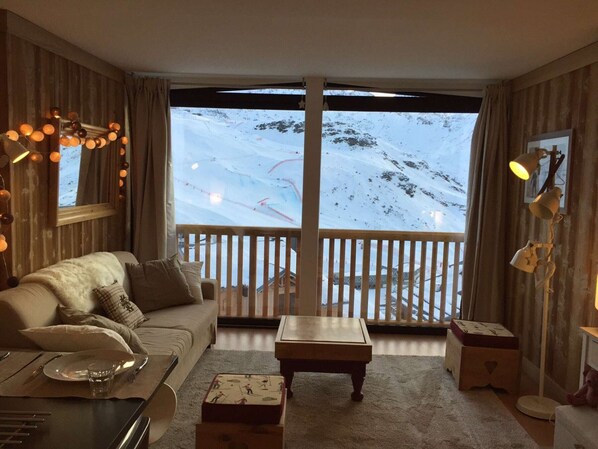 Un salón acogedor con un amplio ventanal con vistas a una montaña nevada.