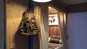 A bedroom with a bed, a hanging bag, and a wooden door.