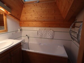 A wooden cabin bathroom with a skylight, a bathtub, a sink, and a towel rack. - Superb ski-in/ski-out duplex with garage and terrace (Arêches-Beaufort)