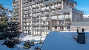 A multi-story hotel with balconies, a ski slope in the background, and snow on the ground. - Beautiful 76m² apartment in Courchevel, near slopes, 3 bedrooms, parking (Courchevel 1550)