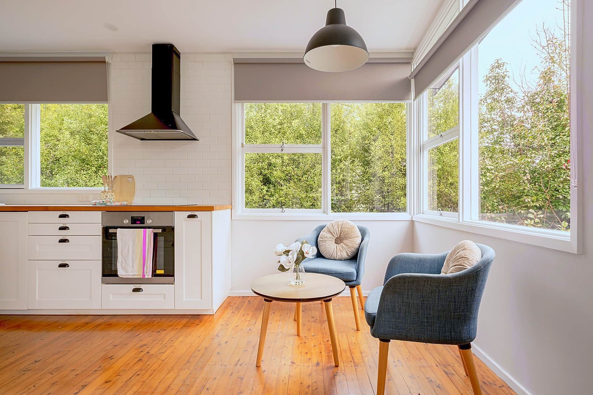 A modern kitchen with white cabinetry, a built-in oven, and a large window overlooking greenery.