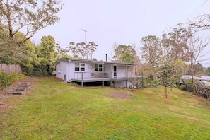 A two-story house with a balcony, surrounded by a grassy yard and trees.