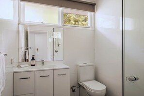 Ein Badezimmer mit Toilette, Waschbecken, Spiegel und Dusche.