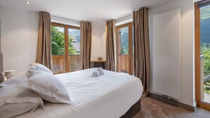 A bedroom with a large bed, wooden headboard, and a view of greenery through the window. - Modern chalet in Méribel with sauna and jacuzzi, 6 bedrooms (Méribel)