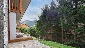 A wooden deck leading to a stone building with a wooden balcony.