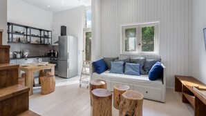 A modern kitchen with a built-in refrigerator, wooden stools, and a dining table.