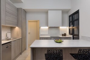 A modern kitchen with a central island, built-in appliances, and a minimalist design. - THIRAMENOUS RESIDENCE - FIVOS SUITE (Athina)